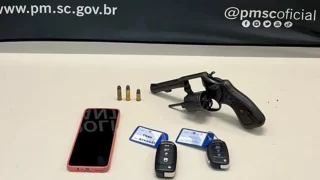 Arma, munições, celular e chaves de veículos que foram apreendidos pela polícia junto com cinco homens presos