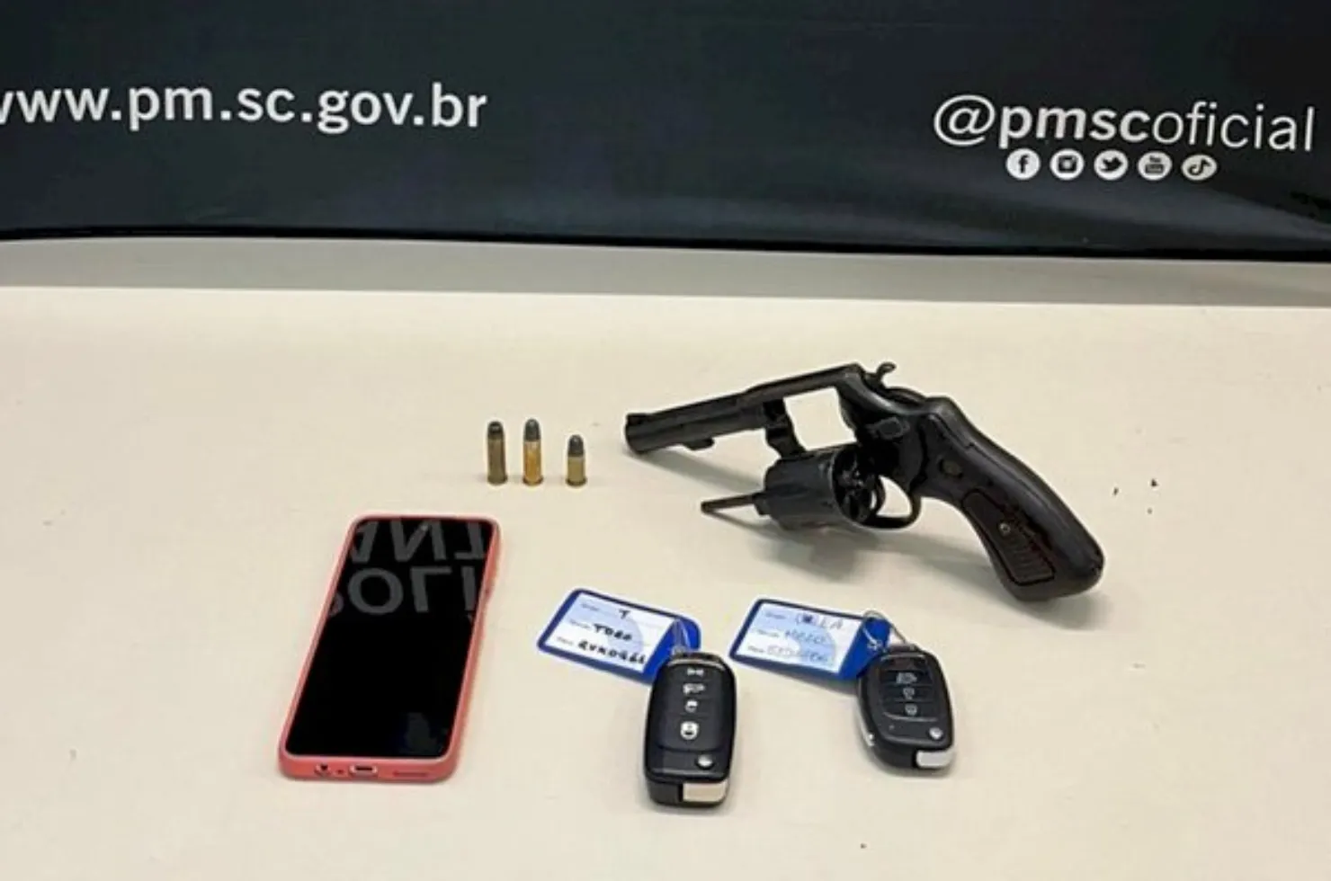 Arma, munições, celular e chaves de veículos que foram apreendidos pela polícia junto com cinco homens presos