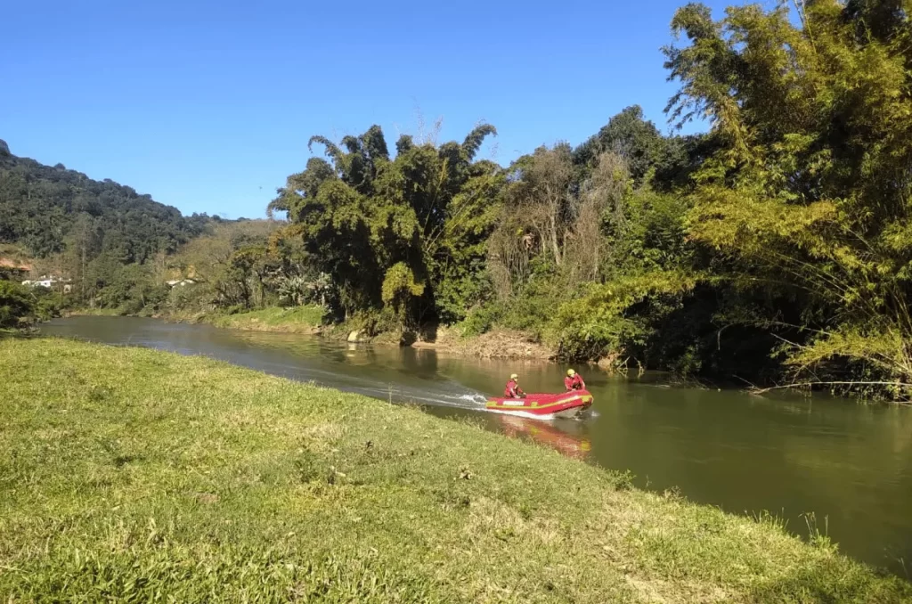 Equipe de topografia e Defesa Civil realizando batimetria com embarcação no rio em Braço do Norte para instalação de estações de monitoramento