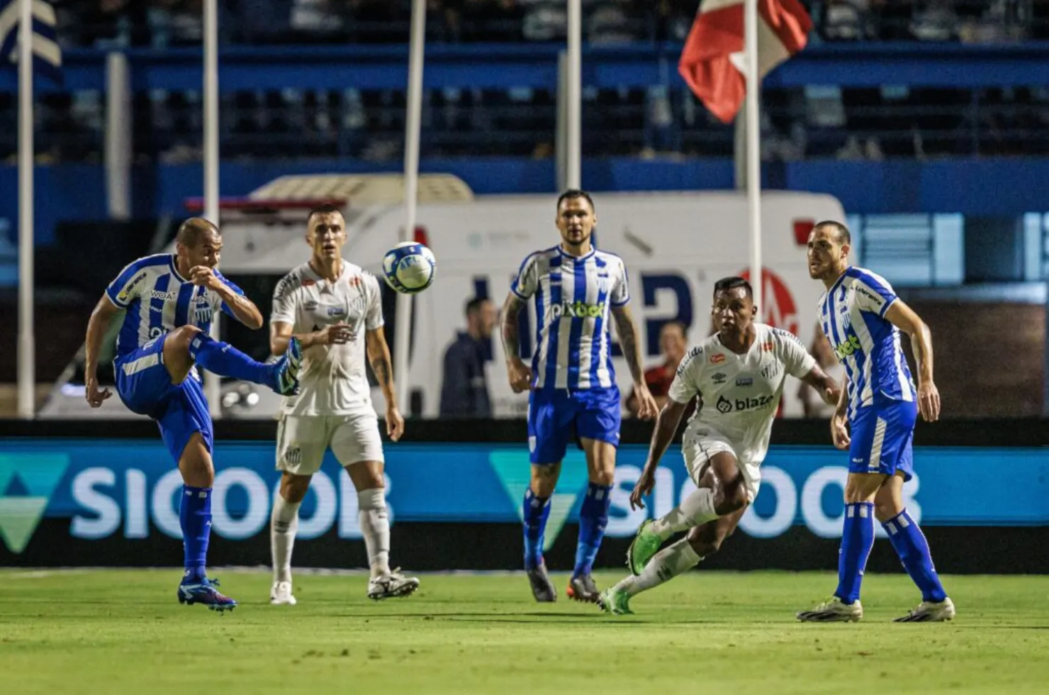 Jogadores de Avaí e Santos disputando bola no primeiro turno da Série B 2024, com torcida ao fundo