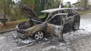 Imagem do veículo Gol G3 preto em chamas sendo atendido pelo Corpo de Bombeiros na rua Manoel José da Cunha, São José