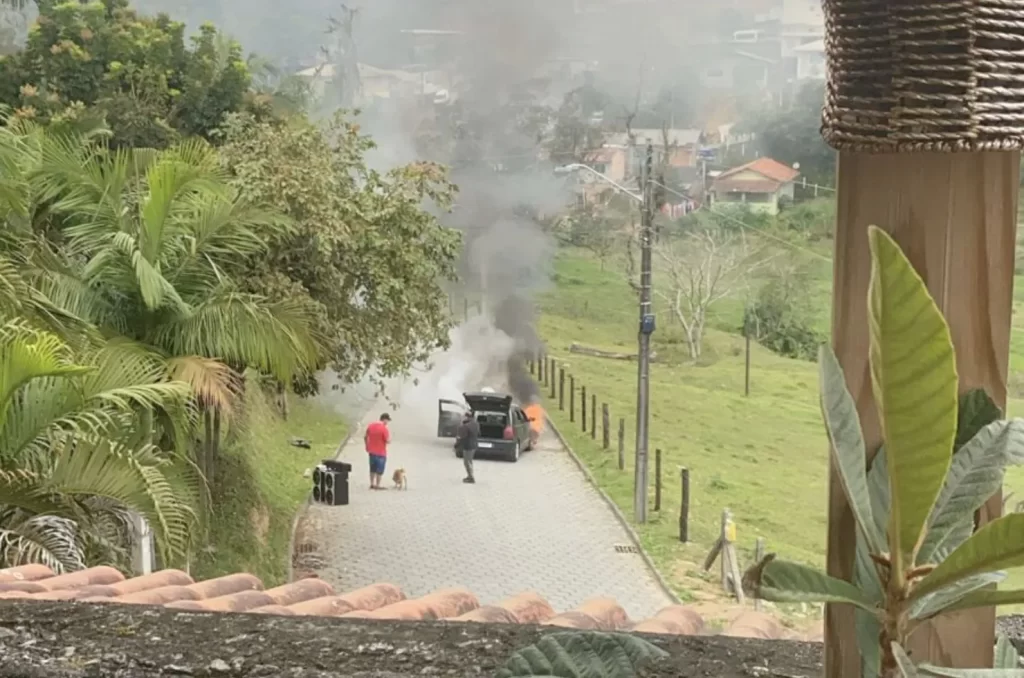 Imagem do veículo Gol G3 preto em chamas sendo atendido pelo Corpo de Bombeiros na rua Manoel José da Cunha, São José