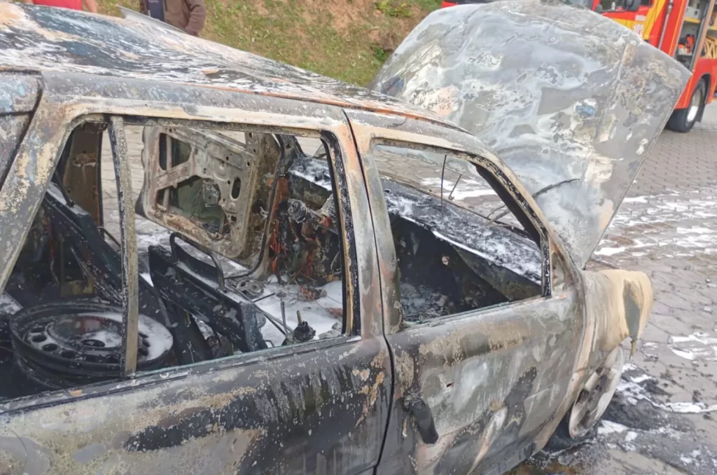 Imagem do veículo Gol G3 preto em chamas sendo atendido pelo Corpo de Bombeiros na rua Manoel José da Cunha, São José