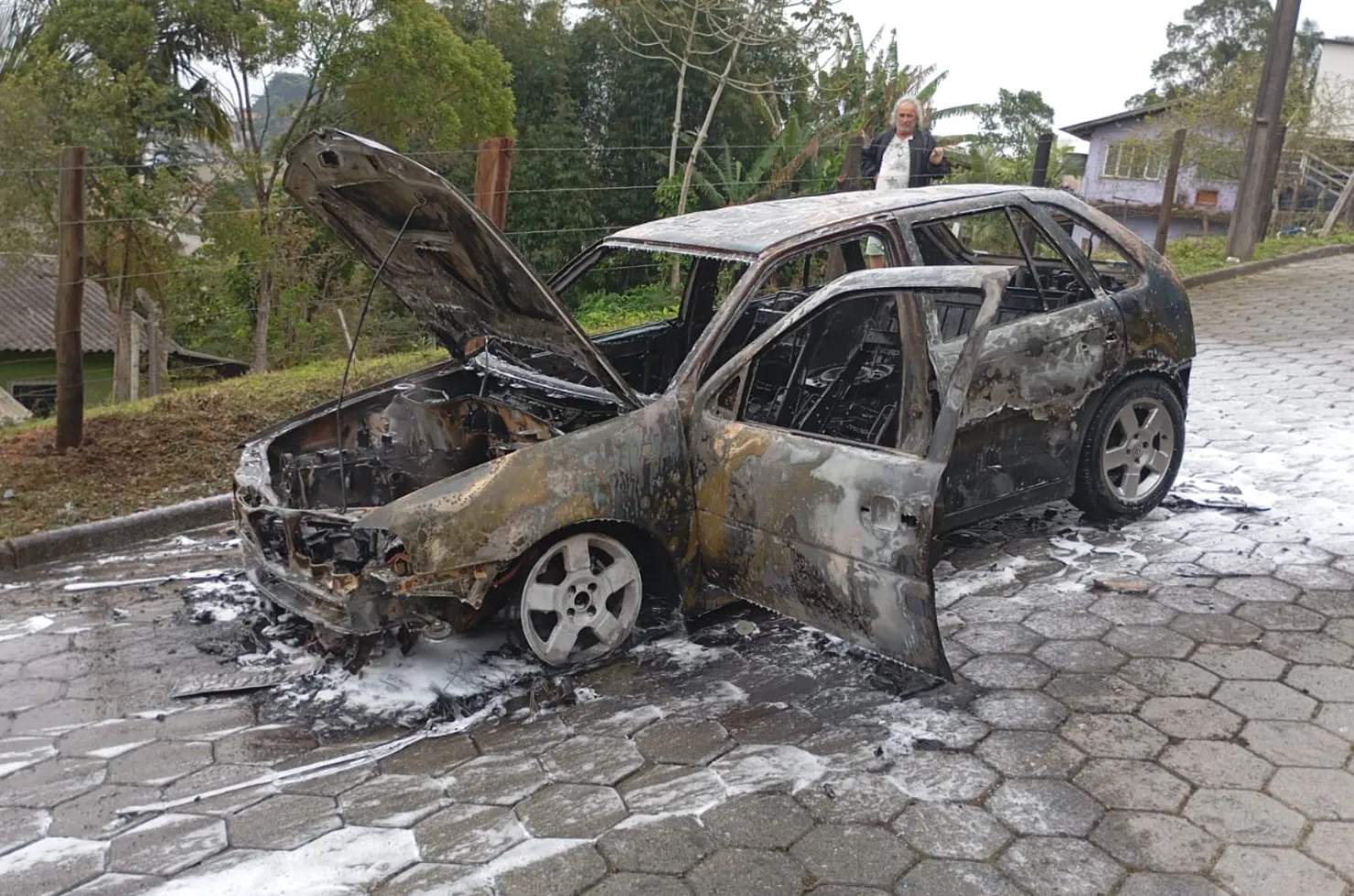 Imagem do veículo Gol G3 preto em chamas sendo atendido pelo Corpo de Bombeiros na rua Manoel José da Cunha, São José