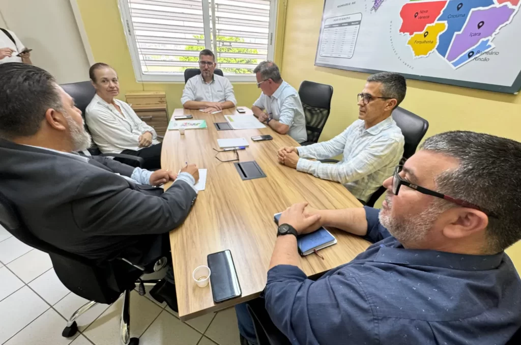 A reunião de reintegração de Criciúma à Amrec, com a presença do prefeito Ricardo Fabris e da prefeita Saionara Corrêa de Carvalho Bora, discutindo políticas públicas
