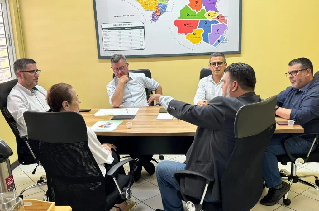 A reunião de reintegração de Criciúma à Amrec, com a presença do prefeito Ricardo Fabris e da prefeita Saionara Corrêa de Carvalho Bora, discutindo políticas públicas