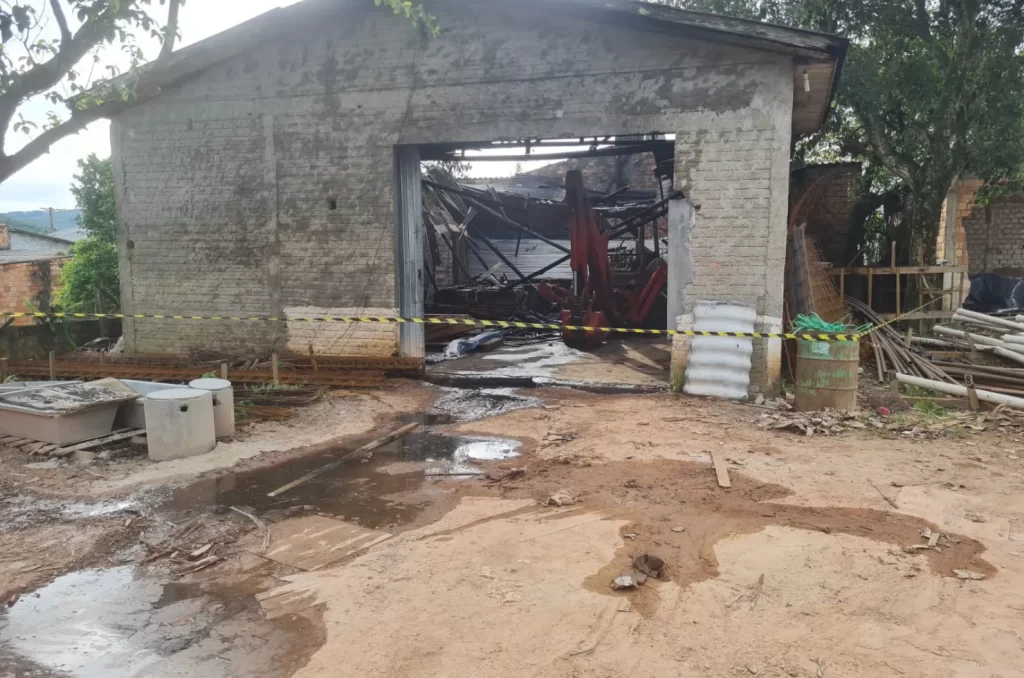 ncêndio em depósito de materiais de construção no bairro Nova Brasília, em Sombrio, com bombeiros controlando as chamas e danos materiais visíveis