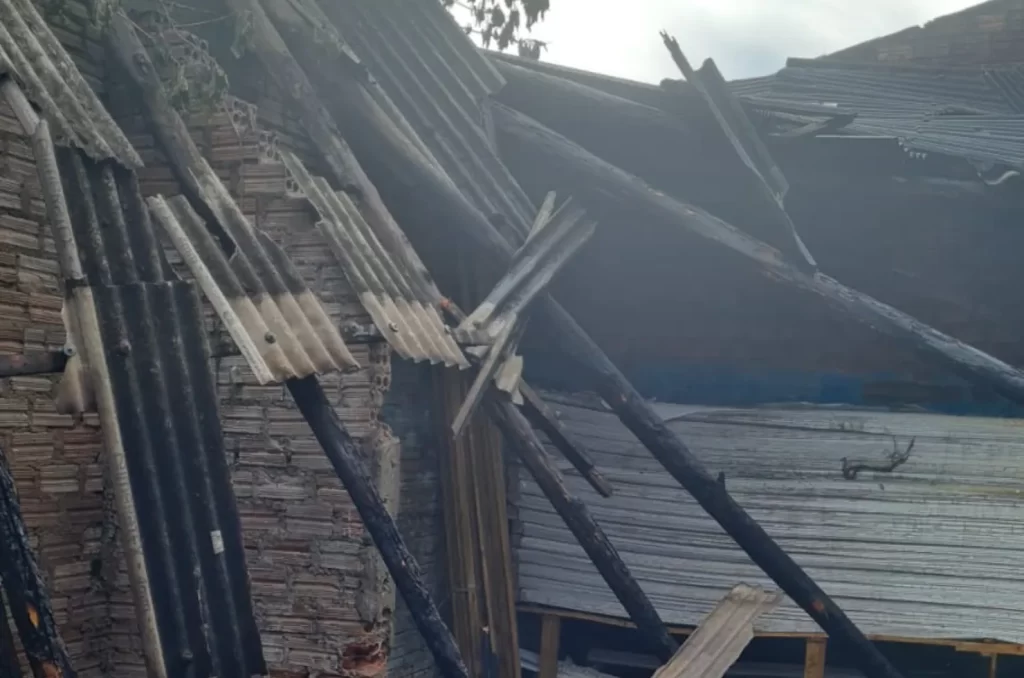 ncêndio em depósito de materiais de construção no bairro Nova Brasília, em Sombrio, com bombeiros controlando as chamas e danos materiais visíveis