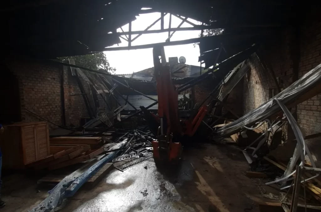ncêndio em depósito de materiais de construção no bairro Nova Brasília, em Sombrio, com bombeiros controlando as chamas e danos materiais visíveis