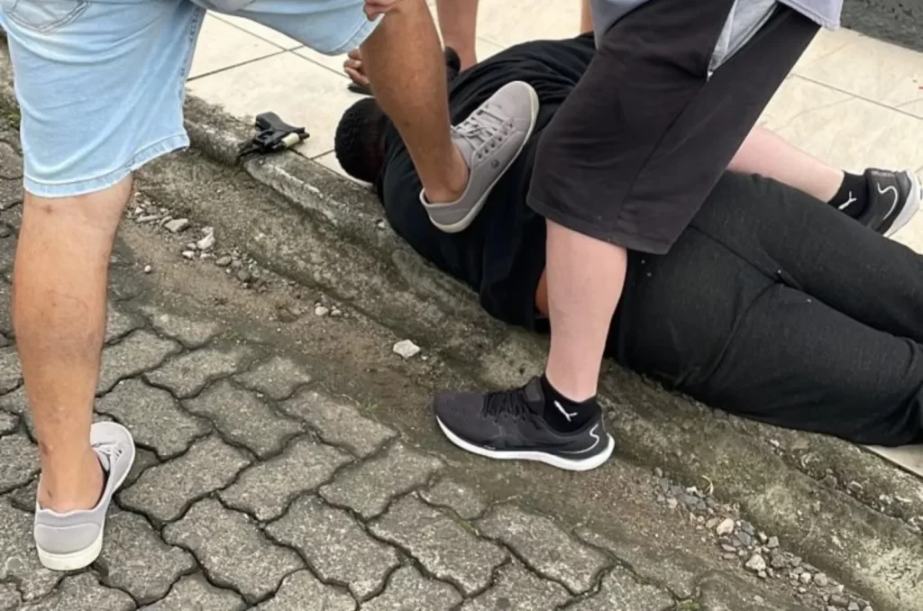 Homem sendo preso após assaltar loja de celulares em Criciúma