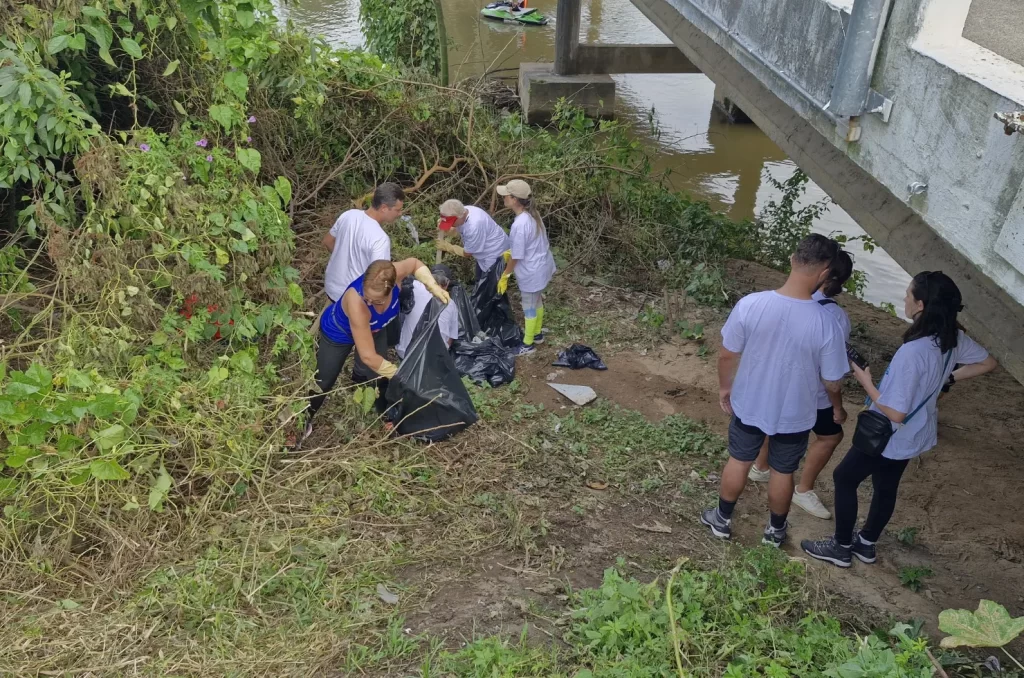 Voluntários participam do mutirão de limpeza no Rio Tubarão, promovido pela prefeitura, recolhendo lixo e revitalizando as margens