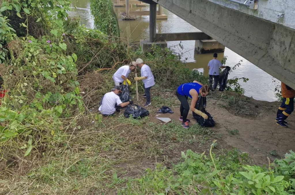 Voluntários participam do mutirão de limpeza no Rio Tubarão, promovido pela prefeitura, recolhendo lixo e revitalizando as margens