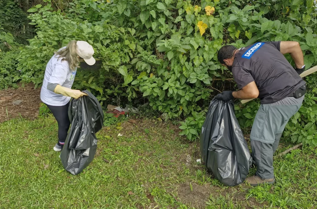 Voluntários participam do mutirão de limpeza no Rio Tubarão, promovido pela prefeitura, recolhendo lixo e revitalizando as margens