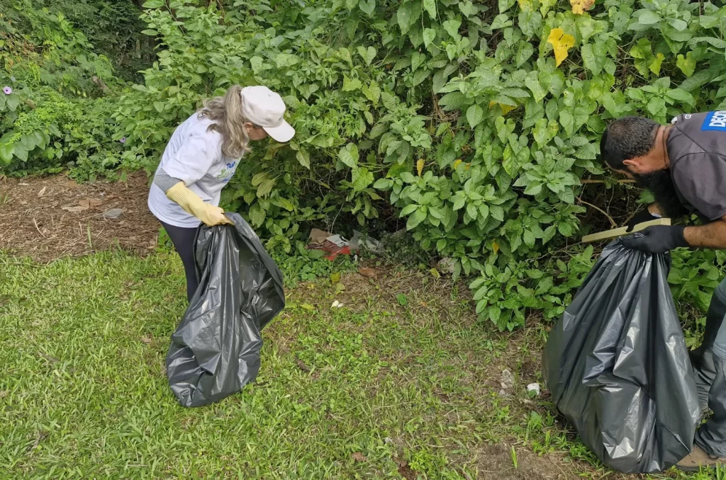 Voluntários participam do mutirão de limpeza no Rio Tubarão, promovido pela prefeitura, recolhendo lixo e revitalizando as margens