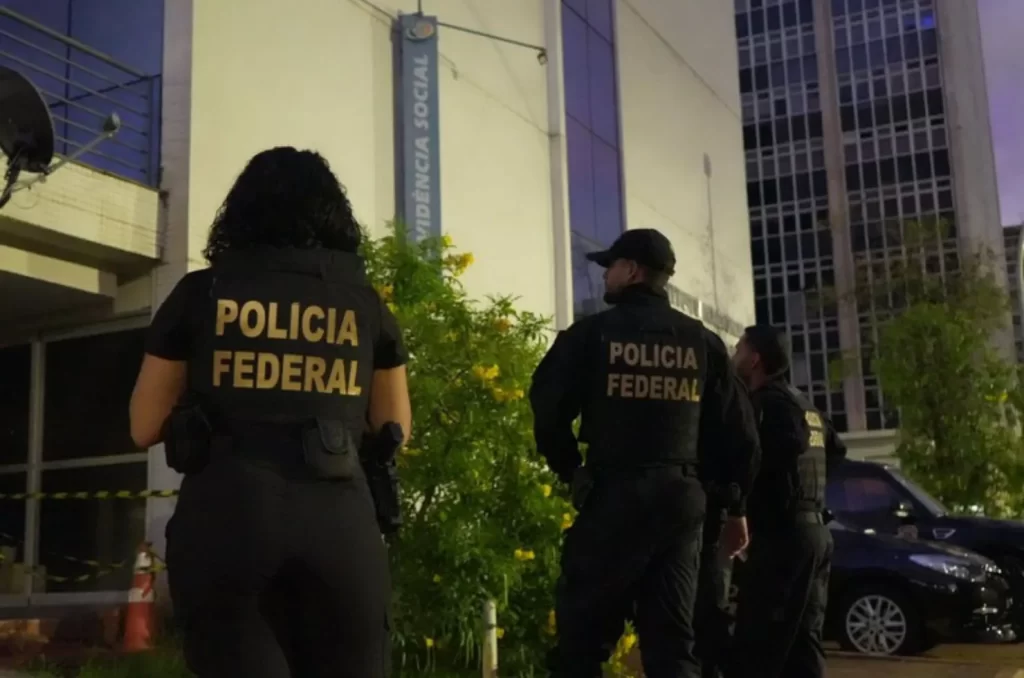 Policiais federais em frente ao prédio do INSS, preparados para uma operação de investigação
