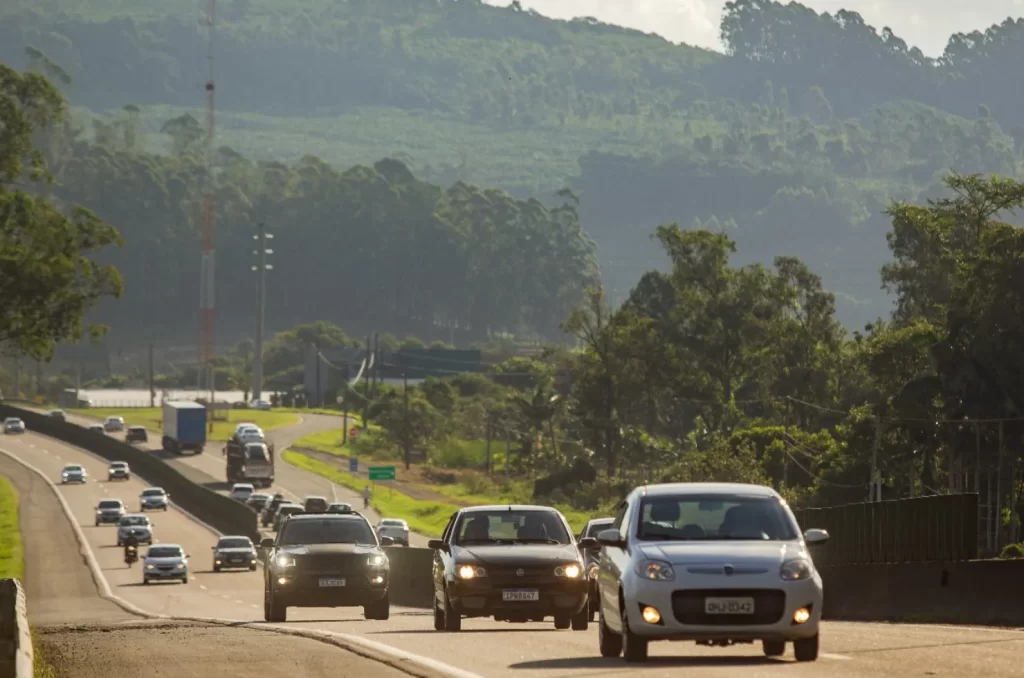 Imagem de fluxo intenso de veículos na BR-101, com carros em movimento constante, destacando a movimentação típica do feriadão